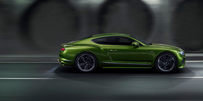  Bentley Leeds Bentley Continental GT coupe in Tourmaline Green paint driving in profile on a dark road