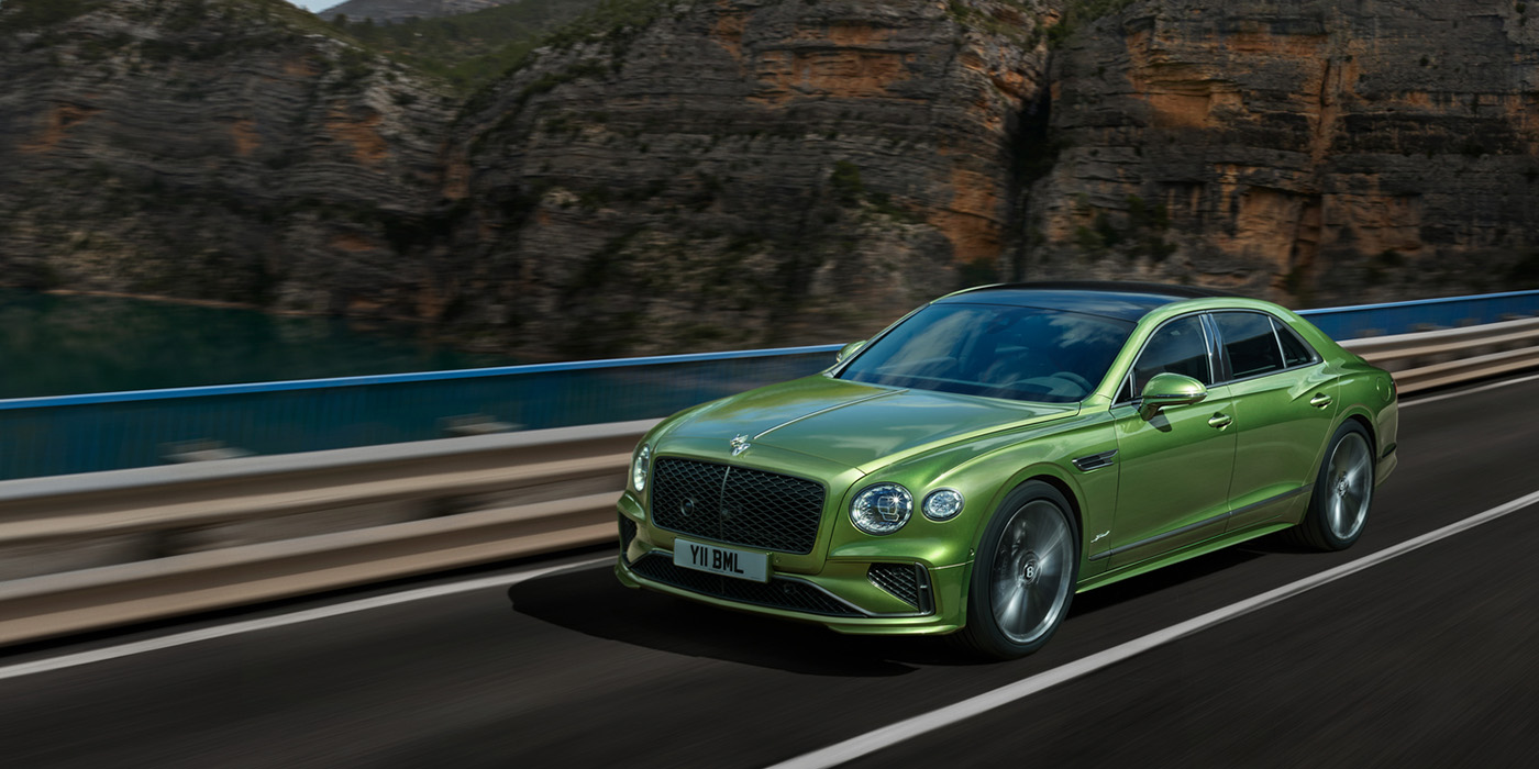 Bentley Leeds Bentley New Flying Spur Speed v8 hybrid sedan driving dynamically on a mountain road in Tourmaline Green paint