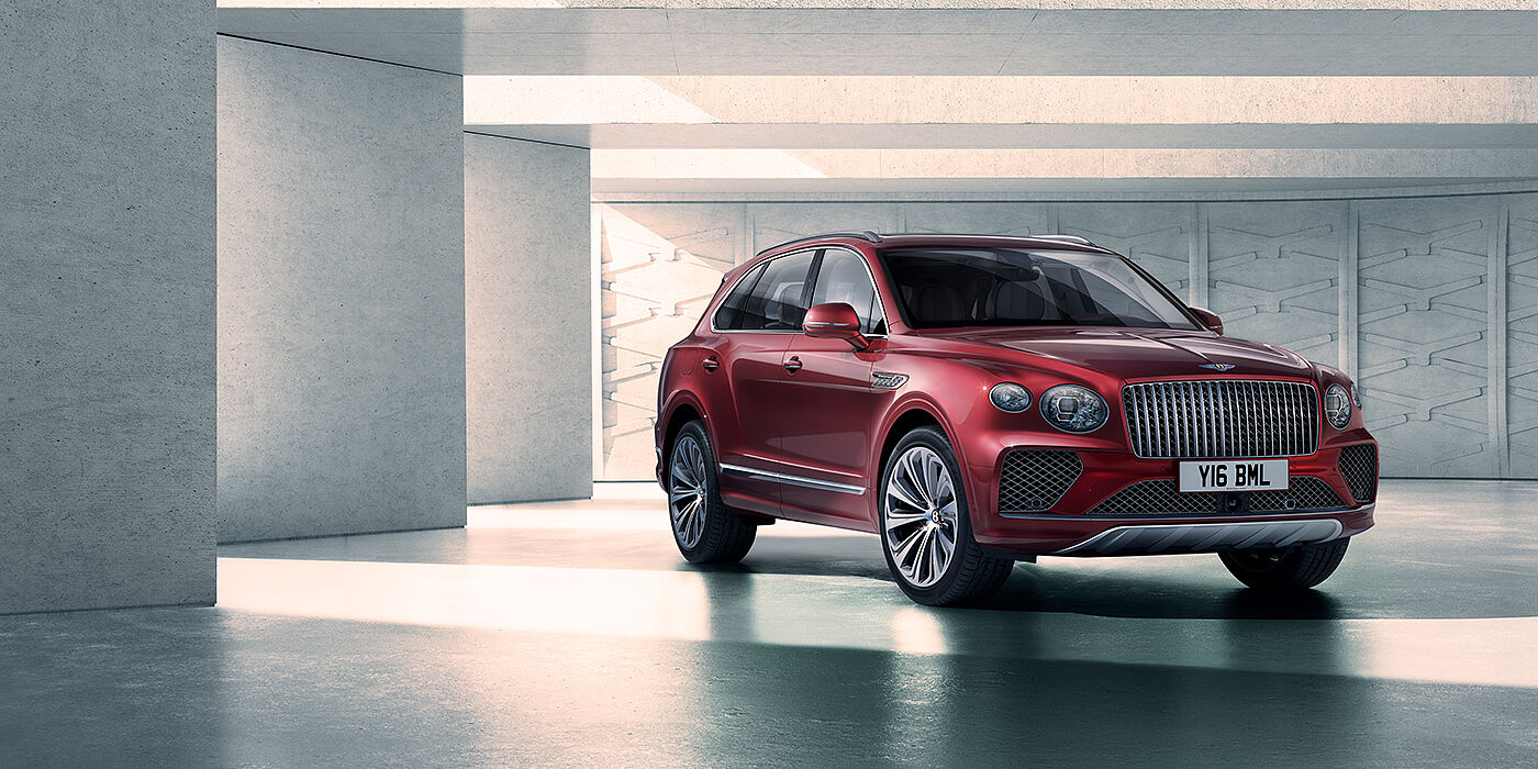 Bentley Leeds Bentley Bentayga Atelier Edition SUV in Rubino Red paint front three quarter against textured concrete wall