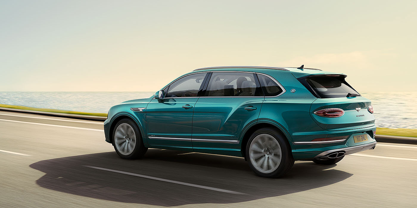Bentley Leeds Bentley Bentayga Extended Wheelbase Azure luxury SUV rear three quarter in Topaz Blue by Mulliner paint, driving on an ocean road.