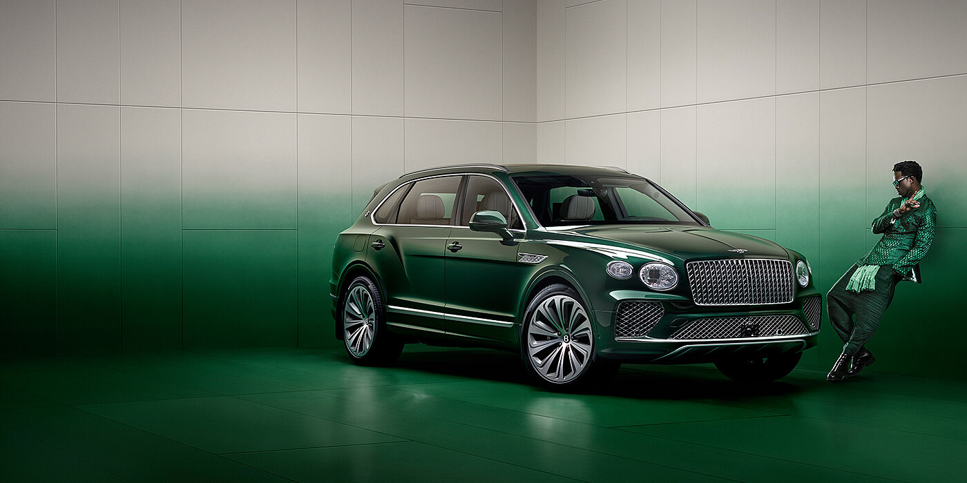 Bentley Leeds Wisdom K leans against wall next to Bentley Bentayga Extended Wheelbase Atelier Edition SUV in Light Emerald green paint