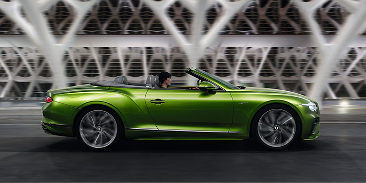 Bentley Leeds Bentley Continental GTC Speed convertible side profile in Tourmaline Green paint driving dynamically on a bridge at night