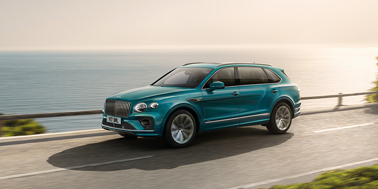 Bentley Leeds Bentley Bentayga Extended Wheelbase Azure SUV in Topaz blue paint driving dynamically by the ocean