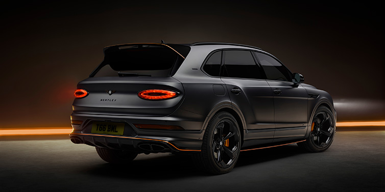 Bentley Leeds Bentley Bentayga S Black Edition SUV rear three quarter in Anthracite Satin paint against a dark red and yellow background