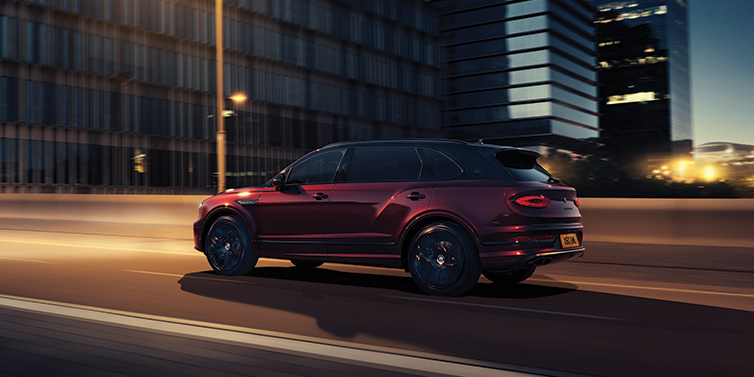 Bentley Leeds Bentley Bentayga Extended Wheelbase Mulliner SUV in Cricket Ball red paint driving dynamically in city at night
