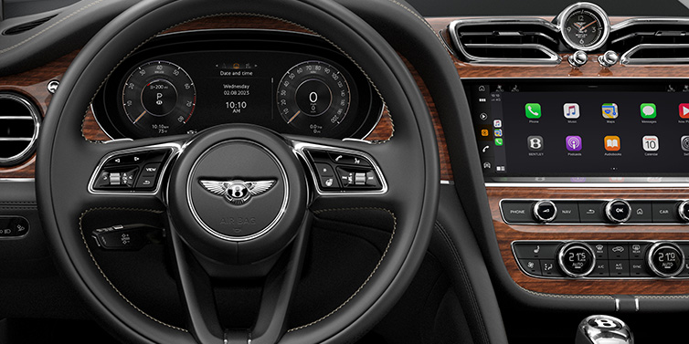 Bentley Leeds Bentley Bentayga SUV front interior detail of steering wheel and driver screens surrounded by Beluga black hide and Crown Cut Walnut veneer